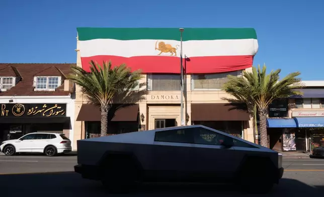 A giant The Lion and Sun flag, the pre-revolution Iranian national flag, decorates the exterior of Damoka rug store along Westwood Boulevard, in the Westwood neighborhood of Los Angeles, at the heart of the largest Iranian diaspora community in the United States, Monday, March 2, 2026. (AP Photo/Damian Dovarganes)