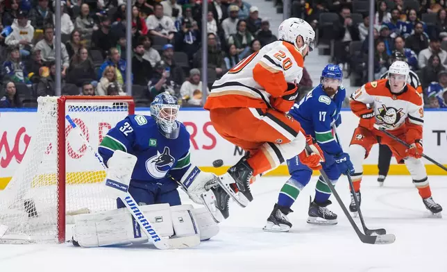 Vancouver Canucks goalie Kevin Lankinen (32) makes the save as Anaheim Ducks' Chris Kreider (20) jumps in front of him during the second period of an NHL hockey game, in Vancouver, on Tuesday, March 24, 2026. (Darryl Dyck/The Canadian Press via AP)