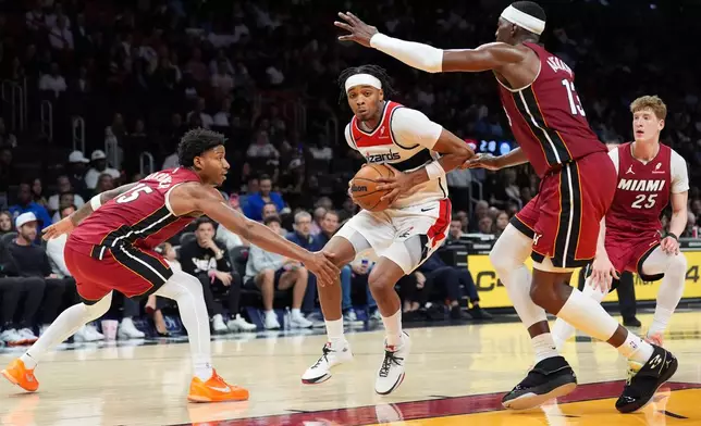 Washington Wizards guard Bilal Coulibaly, center, comes under pressure from Miami Heat forward Myron Gardner (15), center Bam Adebayo (13), and guard Kasparas Jakucionis (25) during the first half of an NBA basketball game, Tuesday, March 10, 2026, in Miami. (AP Photo/Rebecca Blackwell)