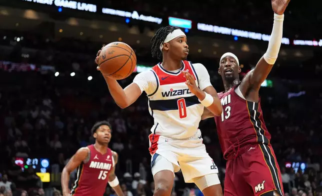 Washington Wizards guard Bilal Coulibaly (0) looks to pass around the defense of Miami Heat center Bam Adebayo (13) during the first half of an NBA basketball game, Tuesday, March 10, 2026, in Miami. (AP Photo/Rebecca Blackwell)