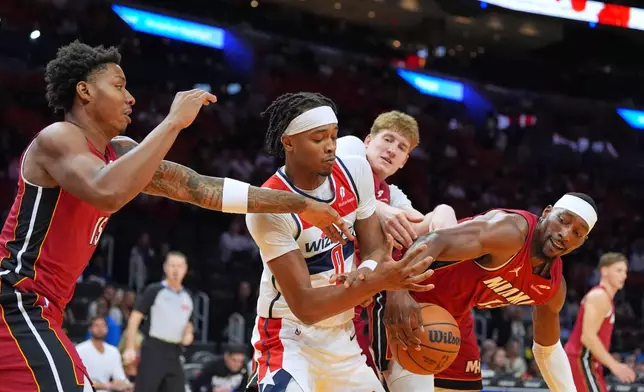 Washington Wizards guard Bilal Coulibaly (0) is stripped of the ball by Miami Heat center Bam Adebayo, right, as forward Myron Gardner (15) and guard Kasparas Jakucionis, back, also defend during the first half of an NBA basketball game, Tuesday, March 10, 2026, in Miami. (AP Photo/Rebecca Blackwell)