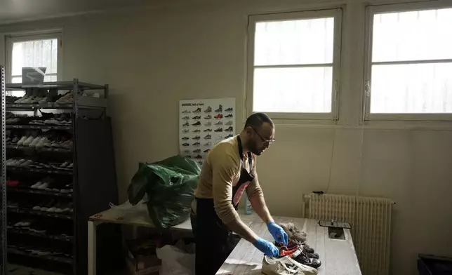 A worker sorts through used sneakers at SneakCoeurZ, a nonprofit organization giving used footwear a second life, in Champs-sur-Marne, east of Paris, Wednesday, March 25, 2026. (AP Photo/Thibault Camus)