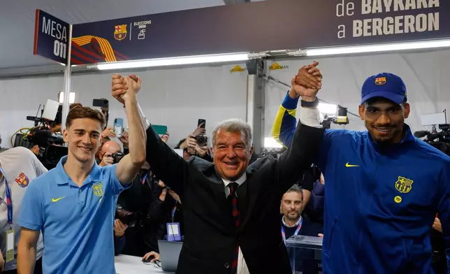 Joan Laporta, center, reacts as he poses with players Gavi, left, and Ronald Araujo after the voting for the election to be president of FC Barcelona in Barcelona, Spain, Sunday, March 15, 2026. (AP Photo/Joan Monfort)