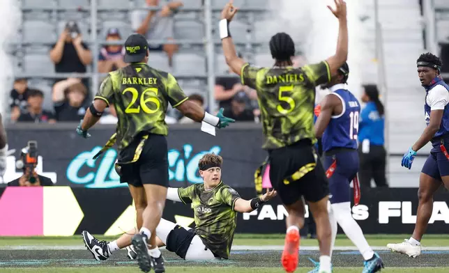 Wildcats FFC's Joe Burrow is greeted by Wildcats FFC's Saquon Barkley and Wildcats FFC's Jayden Daniels after scoring against the U.S. National Flag team during the Fanatics Flag Football Classic, Saturday, March 21, 2026, in Los Angeles. (AP Photo/Caroline Brehman)