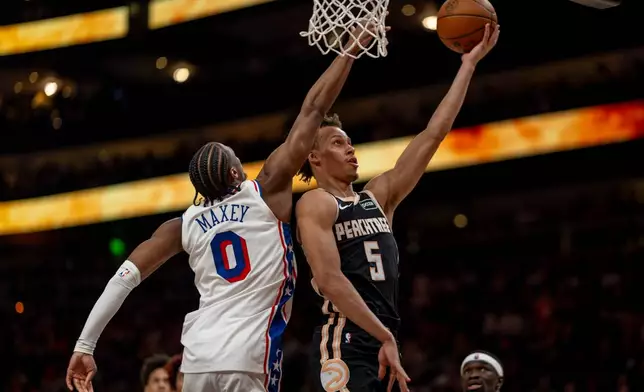 Atlanta Hawks guard Dyson Daniels (5) makes a basket against Philadelphia 76ers guard Tyrese Maxey (0) during the first half of an NBA basketball game, Saturday, March 7, 2026, in Atlanta. (AP Photo/Erik Rank)