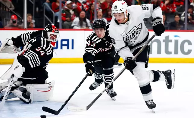 New Jersey Devils goaltender Jake Allen (34) and defenseman Luke Hughes (43) defend against Los Angeles Kings right wing Jared Wright (53) during the first period of an NHL hockey game, Saturday, March 14, 2026, in Newark, N.J. (AP Photo/Noah K. Murray)