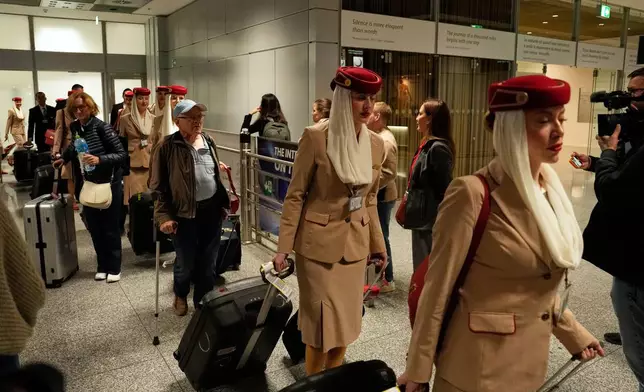 Flight attendants and passengers arrive at the International Airport in Frankfurt, Germany, from Dubai, Tuesday, March 3, 2026. (AP Photo/Michael Probst)