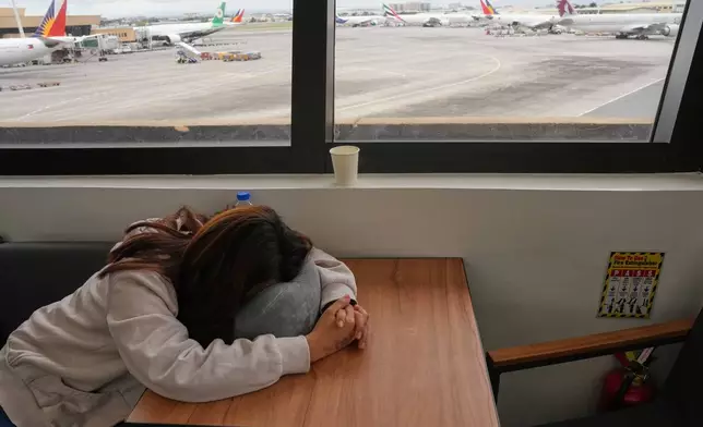 An overseas Filipino worker sleeps as she waits for updates on her cancelled flight to the Middle East at Manila's International Airport, Philippines on Monday, March 2, 2026. (AP Photo/Aaron Favila)