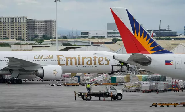 A man works beside a parked Emirates plane at Manila's International Airport, Philippines on Monday, March 2, 2026. (AP Photo/Aaron Favila)