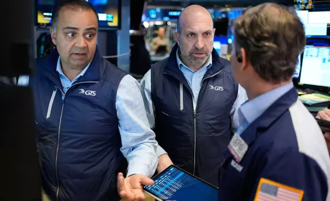 James Denaro, center, and Dilip Patel, left, work on the floor at the New York Stock Exchange in New York, Wednesday, March 25, 2026. (AP Photo/Seth Wenig)