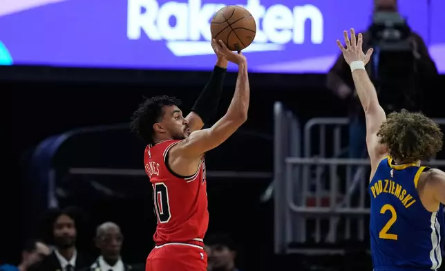 Chicago Bulls guard Tre Jones, left, shoots a 3-point basket over Golden State Warriors guard Brandin Podziemski (2) during the first half of an NBA basketball game, Tuesday, March 10, 2026, in San Francisco. (AP Photo/Godofredo A. Vásquez)
