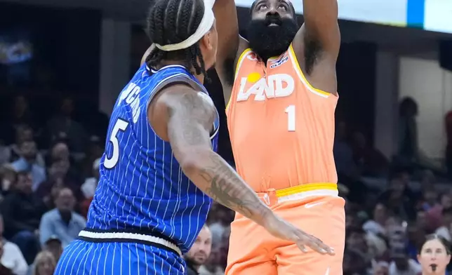 Cleveland Cavaliers guard James Harden (1) shoots as Orlando Magic forward Paolo Banchero (5) defends in the first half of an NBA basketball game in Cleveland, Tuesday, March 24, 2026. (AP Photo/Sue Ogrocki)