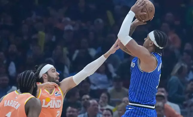 Orlando Magic forward Paolo Banchero, right, shoots over Cleveland Cavaliers guard Max Strus (2) in the first half of an NBA basketball game in Cleveland, Tuesday, March 24, 2026. (AP Photo/Sue Ogrocki)