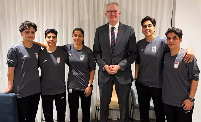 In this photo supplied by Australia's Minister for Home Affairs Tony Burke's office, the Minister Tony Burke, center, poses in an undisclosed location with five Iranian women soccer players who have been granted asylum in Australia, Tuesday, March 10, 2026. (Australia Ministry of Home Affairs via AP)