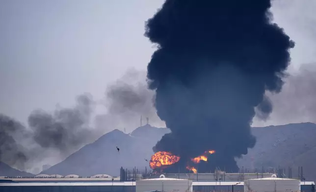 A fire and plume of smoke rise after, according to authorities. debris from an intercepted Iranian drone struck an oil facility in Fujairah, United Arab Emirates, Saturday, March 14, 2026.(AP Photo/Altaf Qadri)
