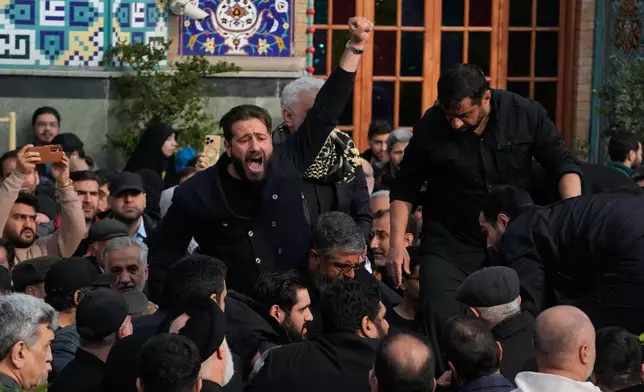 A man chants slogan while the body of Gen. Ali Shamkhani, secretary of Iran's Defense Council and a senior adviser to the Supreme Leader who was killed in a strike, is being buried at the courtyard of the Imamzadeh Saleh shrine in Tehran, Iran, Saturday, March 14, 2026. (AP Photo/Vahid Salemi)