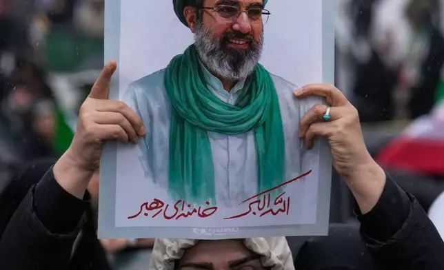 A woman holds up a poster of the Iranian Supreme Leader Ayatollah Mojtaba Khamenei during the annual anti-Israeli Quds Day, or Jerusalem Day, rally in support of Palestinians in Tehran, Iran, Friday, March 13, 2026. (AP Photo/Vahid Salemi)