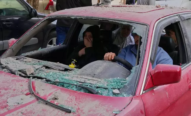 Family members ride in a damaged car, as they flee the site of an Israeli airstrike that hit an apartment building in the southern port city of Sidon, Lebanon, Friday, March 13, 2026. (AP Photo/Mohammed Zaatari)