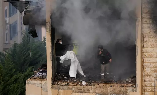 Rescue workers inspect an apartment damaged in an Israeli airstrike as thick smoke fills the building in the southern port city of Sidon, Lebanon, Saturday, March 14, 2026. (AP Photo/Mohammad Zaatari)