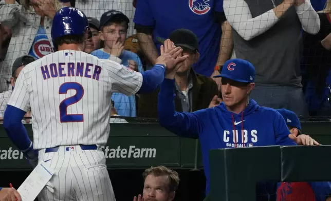 Chicago Cubs' Nico Hoerner (2) is greeted at the dugout after scoring against the Los Angeles Angels during the third inning of a baseball game Monday, March 30, 2026, in Chicago. (AP Photo/David Banks)