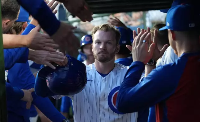 Chicago Cubs' Ian Happ is greeted in the dugout after scoring against the Los Angeles Angels during the first inning of a baseball game Monday, March 30, 2026, in Chicago. (AP Photo/David Banks)