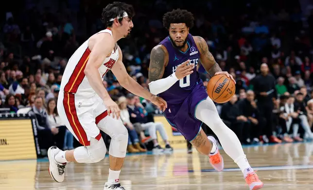 Charlotte Hornets forward Miles Bridges, right, drives to the basket against Miami Heat forward Jaime Jaquez Jr. during the first half of an NBA basketball game, Tuesday, March 17, 2026, in Charlotte, N.C. (AP Photo/Nell Redmond)