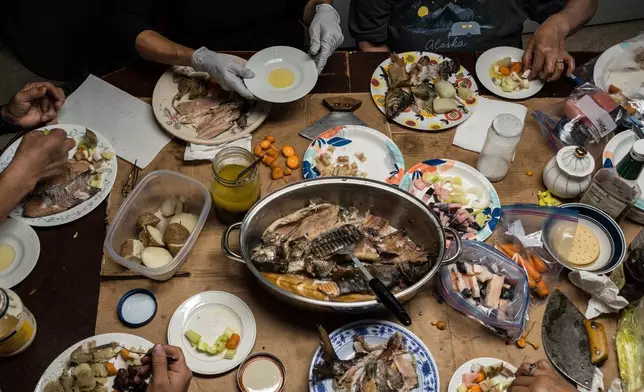FILE - Tristen Pattee and his family eat a meal of beluga whale, bowhead whale, whitefish, moose and seal in Ambler, Alaska, Oct. 2, 2025. (AP Photo/Annika Hammerschlag, File)