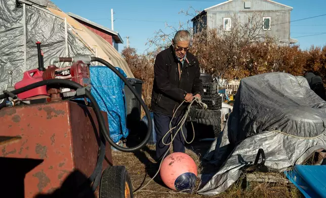 Roswell Schaeffer, an Inupiaq hunter and fisher, organizes hunting equipment next to his covered snowmobile outside his home in Kotzebue, Alaska, Friday, Sept. 26, 2025. (AP Photo/Annika Hammerschlag)