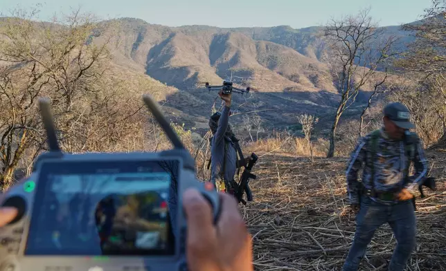 Members of a local self-defense group formed by residents in response to cartel violence fly a drone in Guajes de Ayala, Mexico, Tuesday, March 10, 2026. (AP Photo/Marco Ugarte)