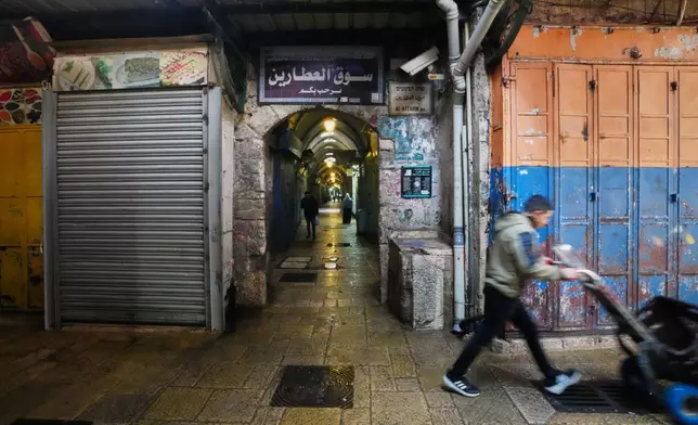 A man pushes a handcart past closed shops in Jerusalem's Old City, Friday, March 27, 2026, as the area remains closed to visitors amid the war with Iran. (AP Photo/Mahmoud Illean)