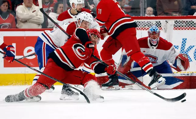 Carolina Hurricanes' Jordan Martinook (48) is taken down by Montréal Canadiens' Kaiden Guhle (21) during the first period of an NHL hockey game in Raleigh, N.C., Sunday, March 29, 2026. (AP Photo/Karl DeBlaker)