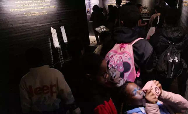 School children visit the National Museum of African American History and Culture's Middle Passage exhibit, including a wooden timber, the artifact at back left, from the slave ship, the São José-Paquete de Africa, Friday, March 6, 2026, in Washington. (AP Photo/Jacquelyn Martin)