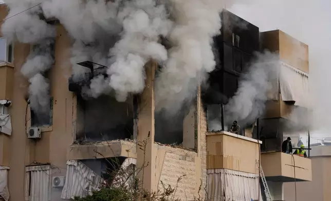 Rescue workers inspect an apartment damaged in an Israeli airstrike as thick smoke fills the building in the southern port city of Sidon, Lebanon, Saturday, March 14, 2026. (AP Photo/Mohammad Zaatari)