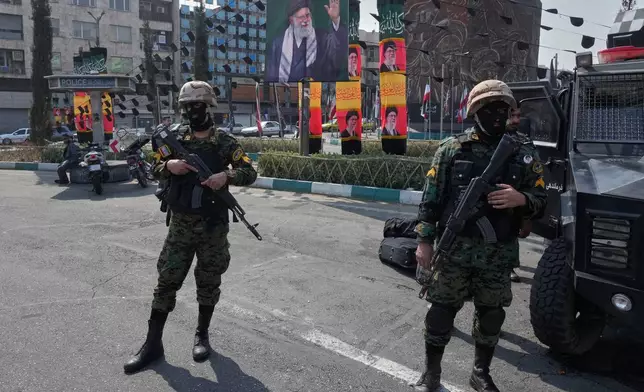 Policemen stand guard next to the banners showing portraits of the late Iranian Supreme Leader Ayatollah Ali Khamenei at the Enqelab-e-Eslami, or Islamic Revolution, square in downtown Tehran, Iran, Saturday, March 14, 2026. (AP Photo/Vahid Salemi)