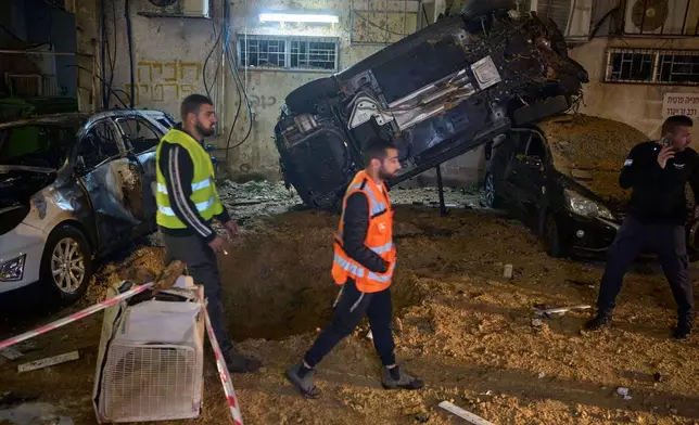 Israeli security forces inspect damage at the site of an Iranian missile strike in Holon, central Israel, Sunday, March 15, 2026. (AP Photo/Ohad Zwigenberg)