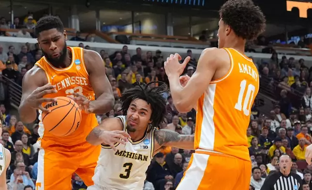 Tennessee's Jaylen Carey (23) and Michigan's Elliot Cadeau (3) reach for the ball as Tennessee's Nate Ament (10) watches during the first half in the Elite Eight of the NCAA college basketball tournament, Sunday, March 29, 2026, in Chicago. (AP Photo/Nam Y. Huh)