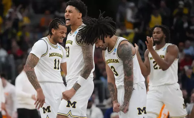 Michigan's Roddy Gayle Jr. (11), Yaxel Lendeborg (23) and Elliot Cadeau (3) celebrate during the first half in the Elite Eight of the NCAA college basketball tournament against Tennessee, Sunday, March 29, 2026, in Chicago. (AP Photo/Erin Hooley)