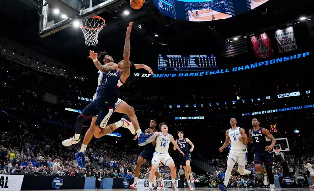 UConn guard Solo Ball scores over Duke guard Cayden Boozer, rear, during the second half in the Elite Eight of the NCAA college basketball tournament, Sunday, March 29, 2026, in Washington. (AP Photo/Stephanie Scarbrough)
