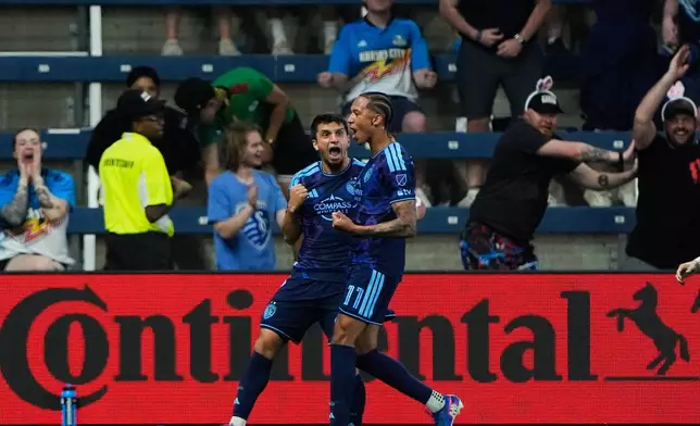 Sporting Kansas City forward Magomed Suleymanov, left, celebrates with forward Calvin Harris (11) after scoring a goal during the first half of an MLS soccer match against the Colorado Rapids, Saturday, March 21, 2026, in Kansas City, Kan. (AP Photo/Charlie Riedel)