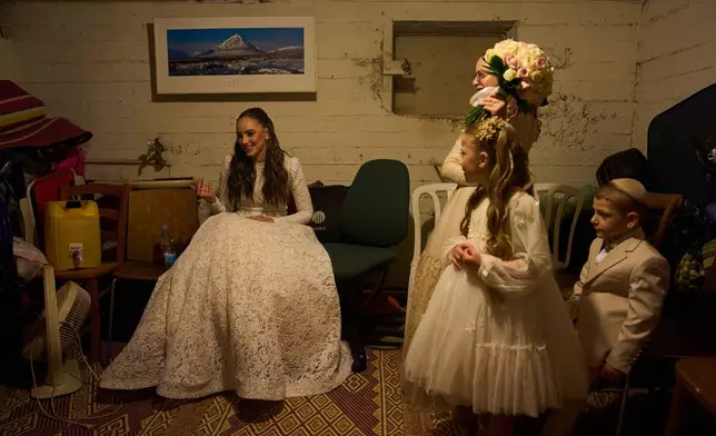 A bride and her family in the midst of a wedding photo session take cover in a bomb shelter after an alert from Israel's Home Front Command warned of missiles fired from Iran toward central Israel, in Ramat Gan, Israel, Thursday, March 19, 2026. (AP Photo/Oded Balilty)
