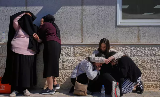 Mourners take cover while air-raid sirens warn of incoming missiles launched by Iran toward Israel during the funeral of Sarah Elimelech and her daughter Ronit who were killed in an Iranian missile attack, in Beit Shemesh, Israel, Monday, March 2, 2026. (AP Photo/Ohad Zwigenberg)