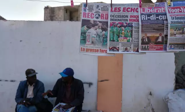 Front pages of newspapers reporting on the Confederation of African Football decision stripping the Senegal national football team of their Africa Cup of Nations title and awarding it to the Morocco national football team in Dakar, Senegal, Wednesday, March 18, 2026. (AP Photo/Misper Apawu)