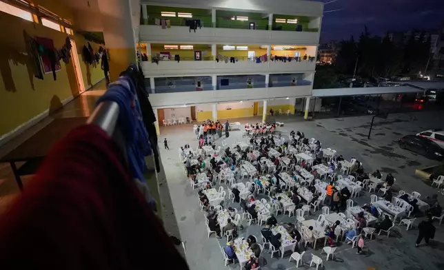Displaced people who fled Israeli strikes from south Lebanon, gather for Iftar, the Ramadan fast-breaking meal, at a school playground turned into a shelter, in the southern port city of Sidon, Lebanon, Monday, March 16, 2026. (AP Photo/Mohammed Zaatari)