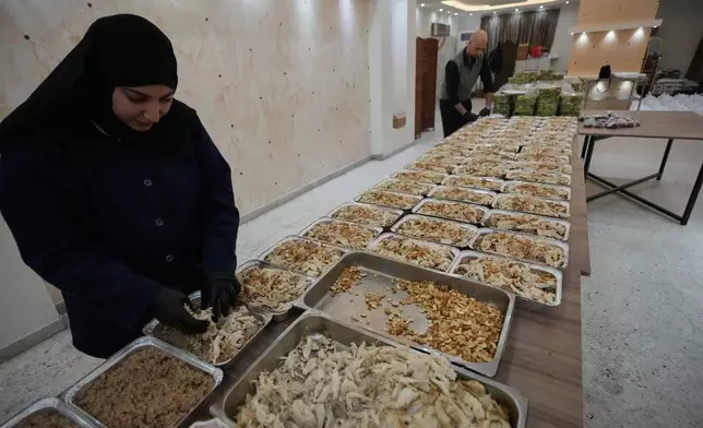 Volunteers prepare meals to be distributed for displaced people who fled Israeli strikes from south Lebanon at al-Rahma centre, in the southern port city of Sidon, Lebanon, Saturday, March 14, 2026. (AP Photo/Mohammed Zaatari)