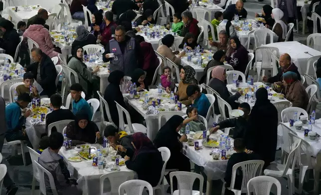Displaced people who fled Israeli strikes from south Lebanon, gather for iftar, the Ramadan fast-breaking meal, at a school playground turned into a shelter, in the southern port city of Sidon, Lebanon, Monday, March 16, 2026. (AP Photo/Mohammed Zaatari)