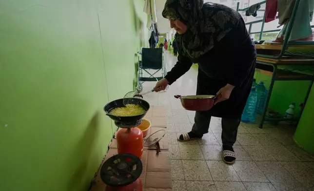 A displaced woman who fled Israeli strikes from south Lebanon, prepares food for Iftar, the Ramadan fast-breaking meal, at a school turned into a shelter, in the southern port city of Sidon, Lebanon, Saturday, March 14, 2026. (AP Photo/Mohammed Zaatari)