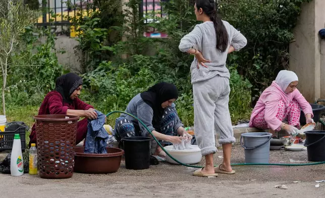 Displaced women who fled Israeli strikes from south Lebanon, wash their laundries at a school playground turned into a shelter, in the southern port city of Sidon, Lebanon, Saturday, March 14, 2026. (AP Photo/Mohammed Zaatari)