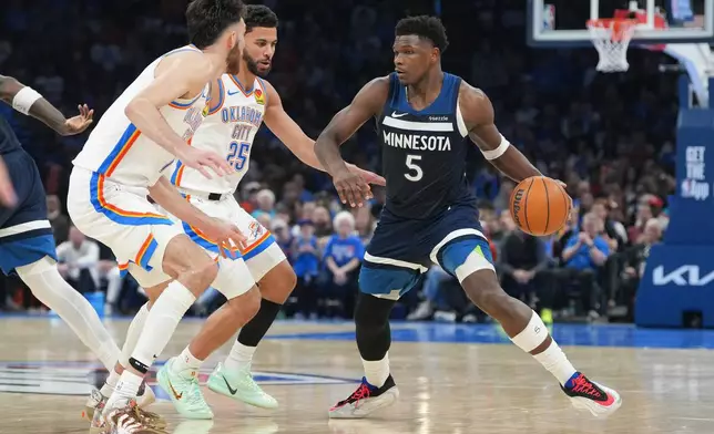 Minnesota Timberwolves guard Anthony Edwards, right, looks for an opening past Oklahoma City Thunder center Chet Holmgren, left, and guard Ajay Mitchell, center, during the second half of an NBA basketball game, Sunday, March 15, 2026, in Oklahoma City. (AP Photo/Kyle Phillips)