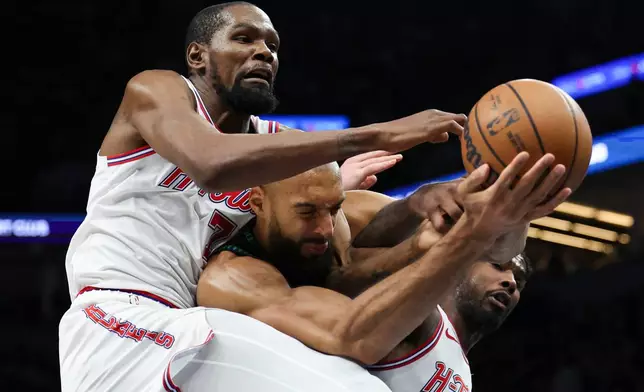 Houston Rockets forward Kevin Durant (7), Minnesota Timberwolves center Rudy Gobert, center, and Houston Rockets guard Amen Thompson, right, compete for a rebound during the first half of an NBA basketball game, Wednesday, March 25, 2026, in Minneapolis. (AP Photo/Ellen Schmidt)