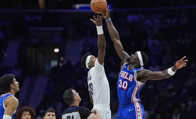 Philadelphia 76ers' Adem Bona (30) tips the ball past Memphis Grizzlies' Olivier-Maxence Prosper during the first half of an NBA basketball game Tuesday, March 10, 2026, in Philadelphia. (AP Photo/Matt Rourke)